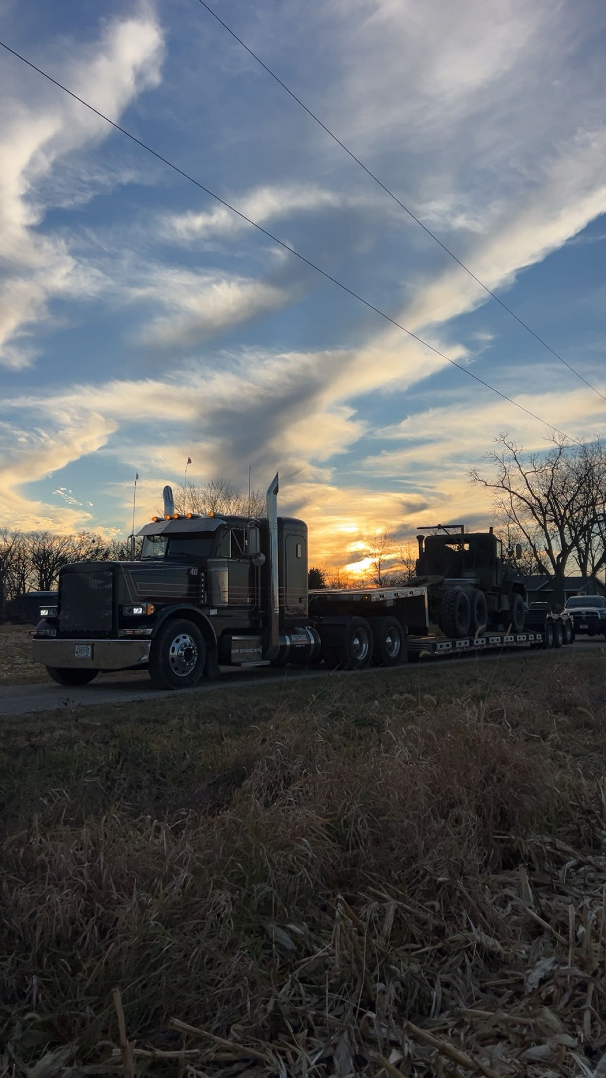 Mittelstadt LLC lowboy transporting equipment at sunset