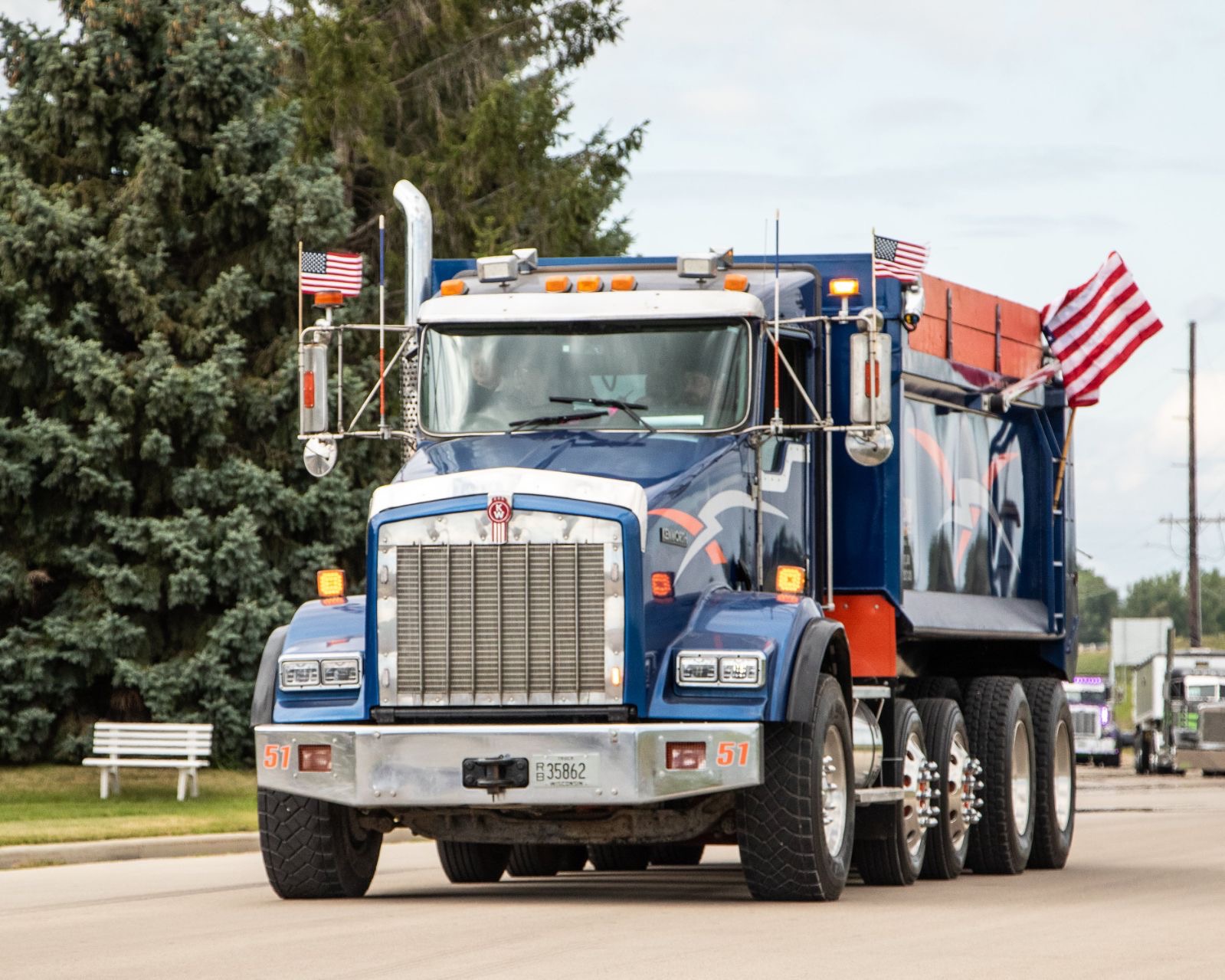 Mittelstadt LLC blue quad-axle dump truck displaying American flags in a local parade